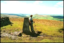 Anne at the trig point on Shining Tor with Shutlingsloe beyond.